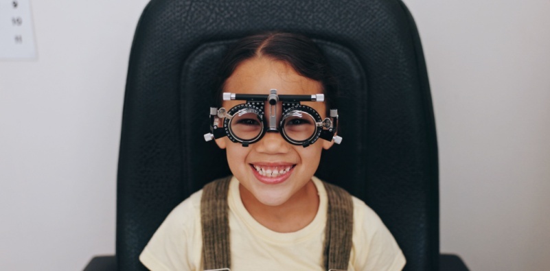 A young girl at the eye doctors wearing a trial frame as part of the eye test.