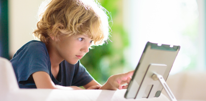 Child using a digital device, illustrating screen time and digital eye strain caused by reduced blinking