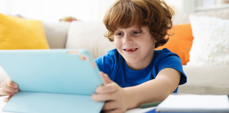 A young boy using a tablet while sat on the floor in his lounge.