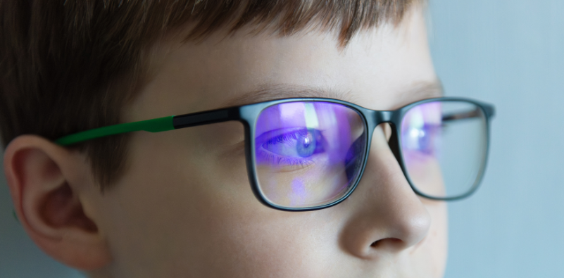A close-up of a child wearing a pair of eyeglasses with an anti-reflective coating