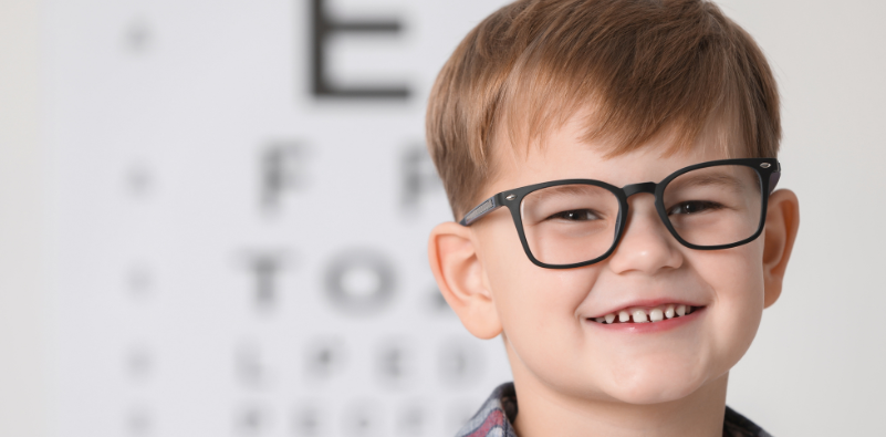 Child wearing glasses while standing in front of an eye chart