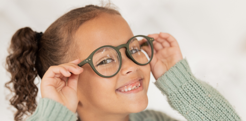 Child adjusting a pair of round eyeglasses