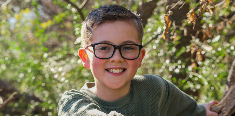 Smiling child wearing pink kids' glasses.