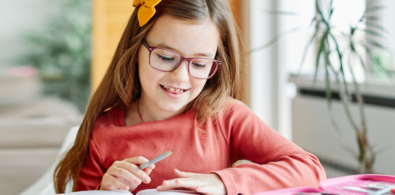 Child wearing glasses while doing homework at home