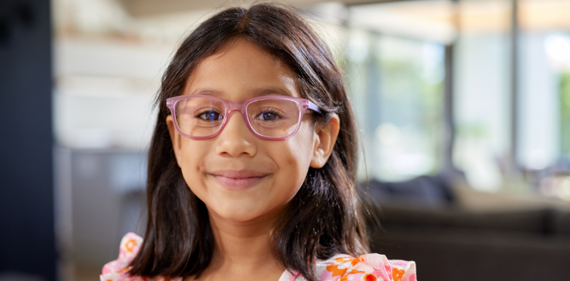 Smiling child wearing pink kids' glasses.