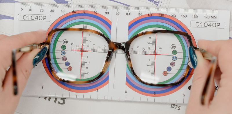 Optician measuring eyeglass lenses with a ruler for an accurate optical fitting.
